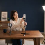 女性配信者が照明と二台のスマートフォンを見ながらカメラ位置を調整している